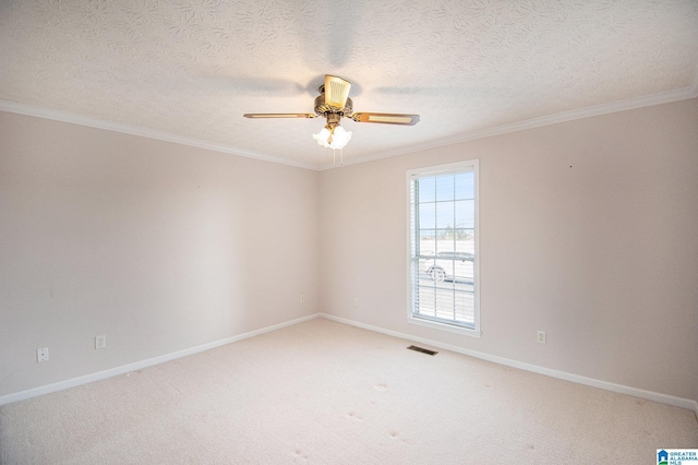 empty room featuring crown molding, light colored carpet, baseboards, visible vents, and a ceiling fan