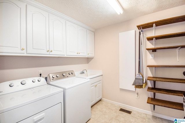 laundry area with washer and clothes dryer, a sink, a textured ceiling, visible vents, and cabinet space