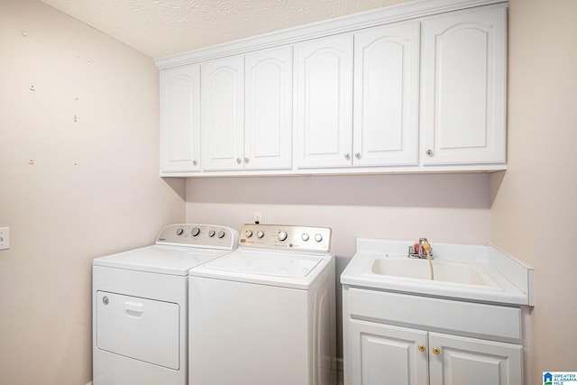 laundry room with washing machine and dryer, a textured ceiling, a sink, and cabinet space