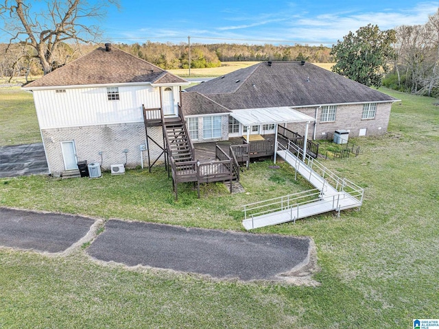 exterior space featuring a lawn, brick siding, stairway, and a deck