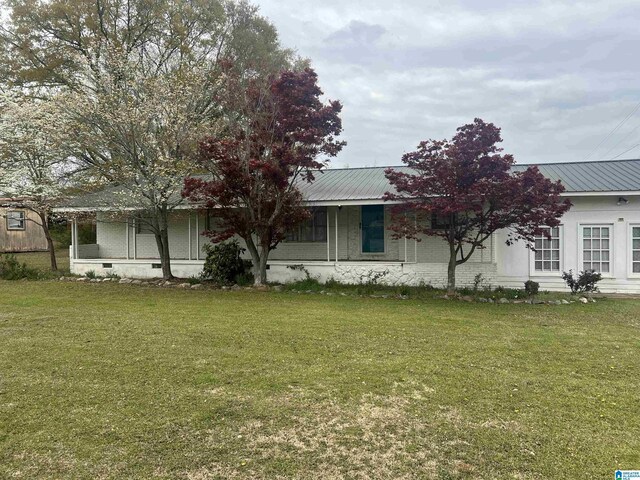 view of front facade with metal roof, crawl space, and a front yard