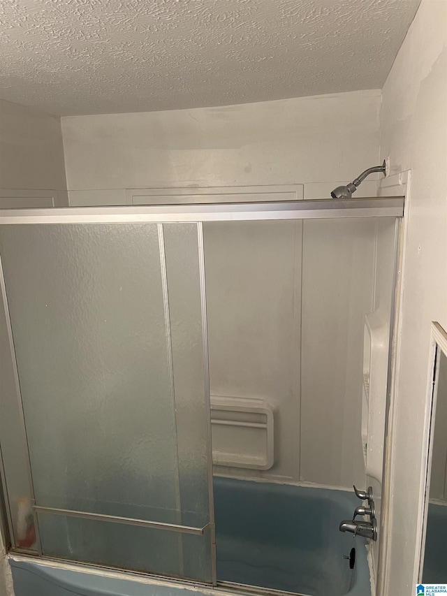 bathroom featuring enclosed tub / shower combo and a textured ceiling
