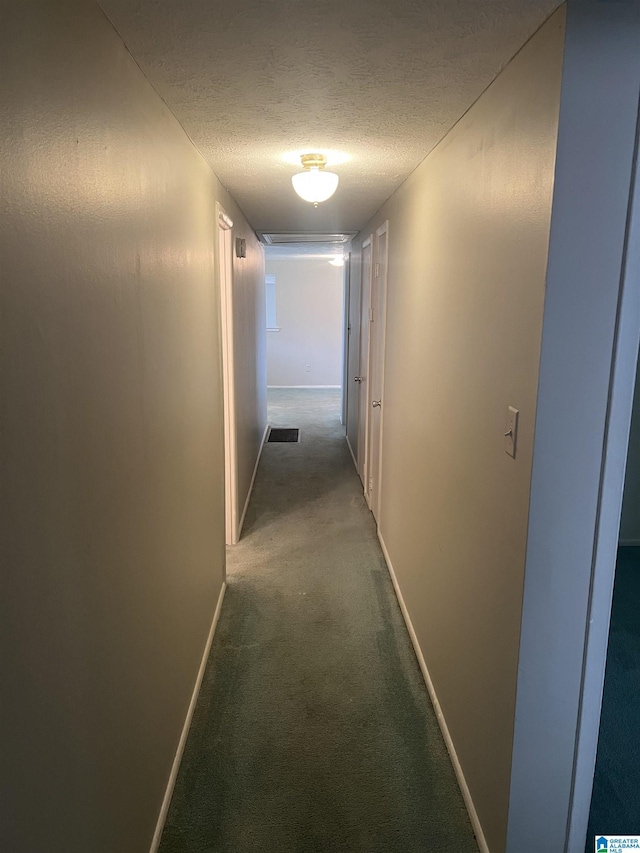 corridor featuring carpet flooring, visible vents, baseboards, and a textured ceiling