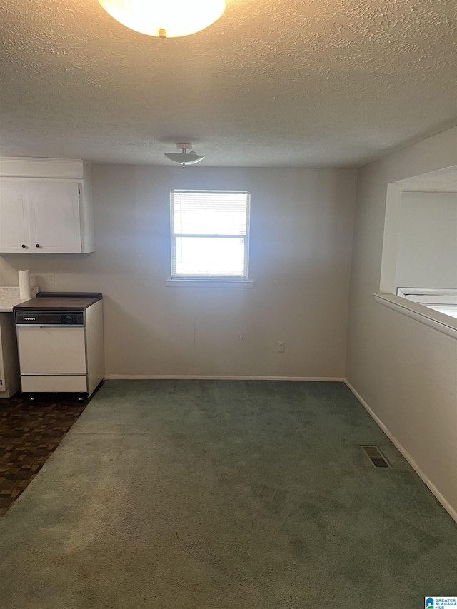 interior space with dark carpet, baseboards, a textured ceiling, and visible vents