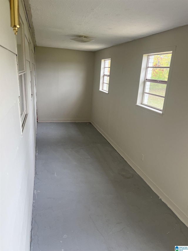spare room featuring concrete flooring, baseboards, and a textured ceiling