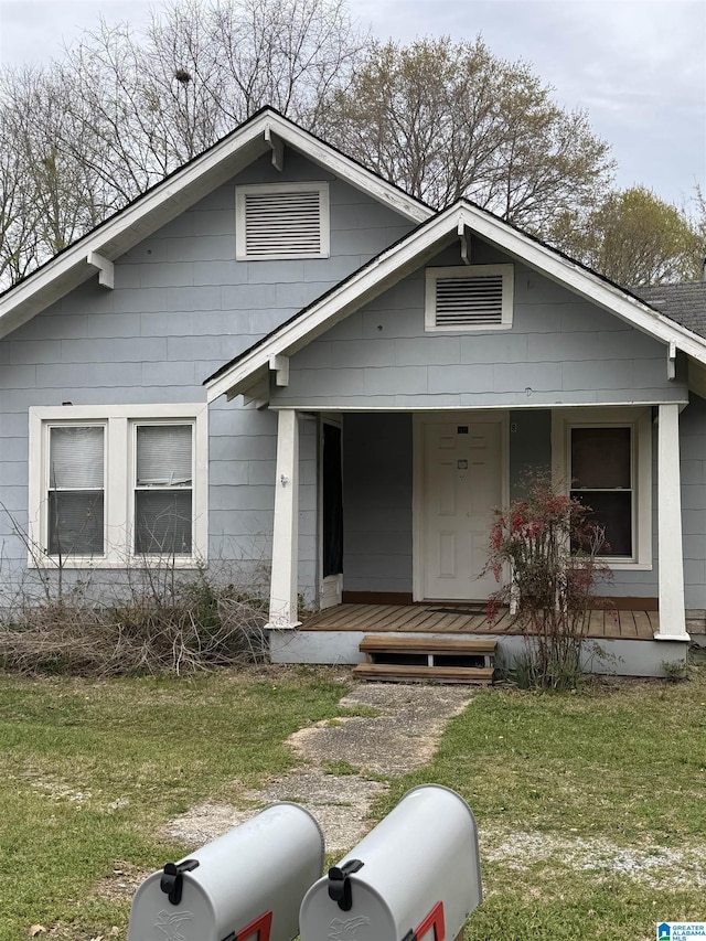 bungalow-style home with covered porch and a front yard
