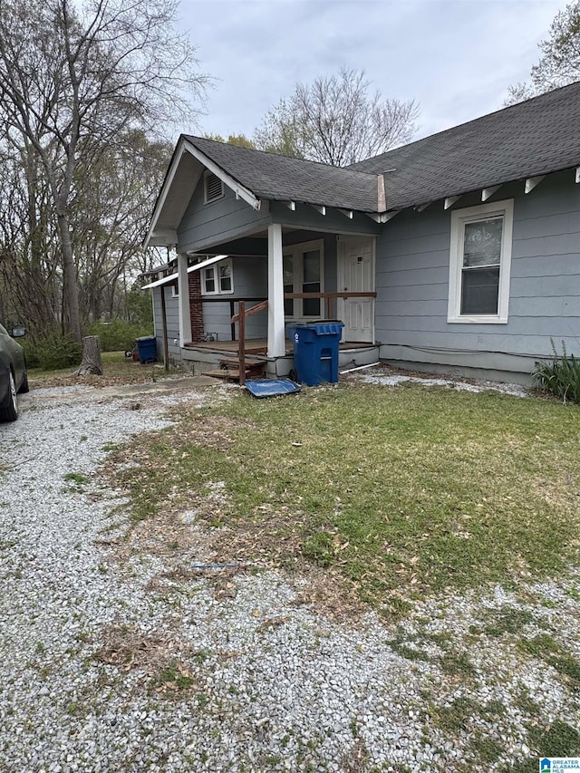 exterior space featuring covered porch, roof with shingles, and a lawn