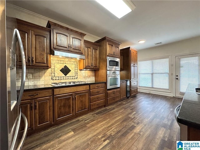 11433 Belle Meade Way, Northport, AL 35475 - kitchen with dark wood finished floors, tasteful backsplash, under cabinet range hood, appliances with stainless steel finishes, and beverage cooler