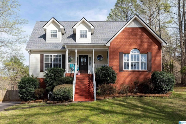 cape cod-style house featuring brick siding, roof with shingles, a porch, and a front lawn