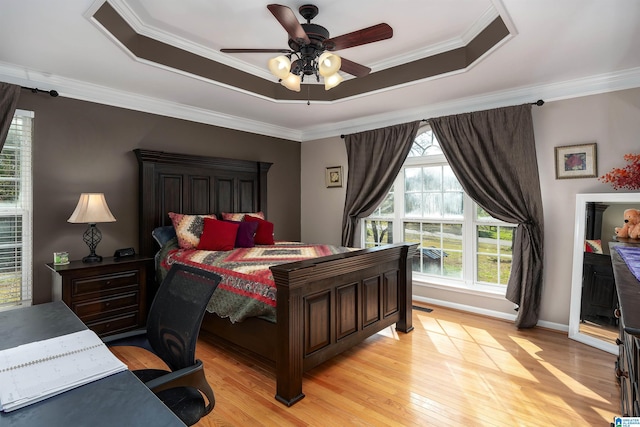 bedroom with visible vents, a raised ceiling, a ceiling fan, crown molding, and light wood finished floors
