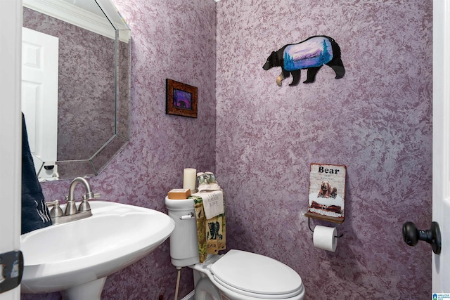 bathroom featuring wallpapered walls, a sink, and toilet