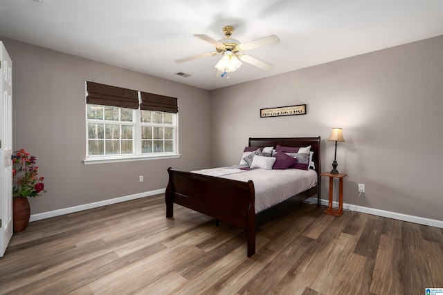bedroom with visible vents, baseboards, a ceiling fan, and wood finished floors