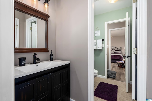 ensuite bathroom with ensuite bathroom, baseboards, toilet, vanity, and tile patterned floors