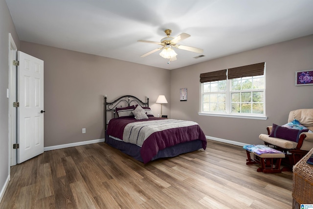 bedroom with visible vents, baseboards, a ceiling fan, and wood finished floors