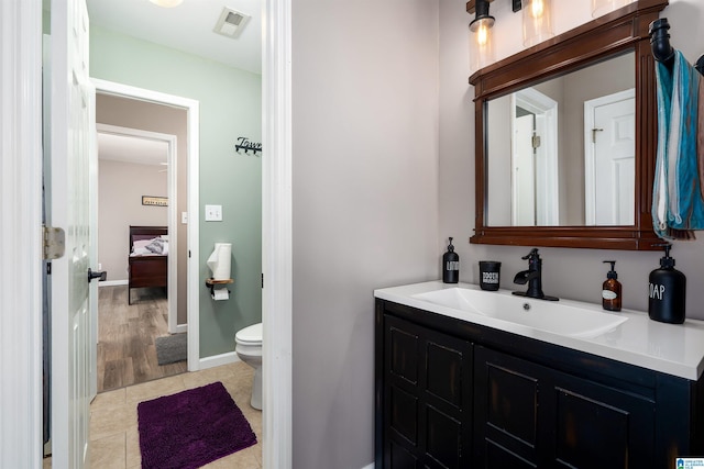 bathroom with vanity, visible vents, toilet, tile patterned floors, and baseboards