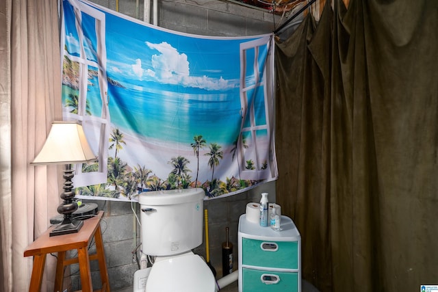 bathroom with toilet and concrete block wall
