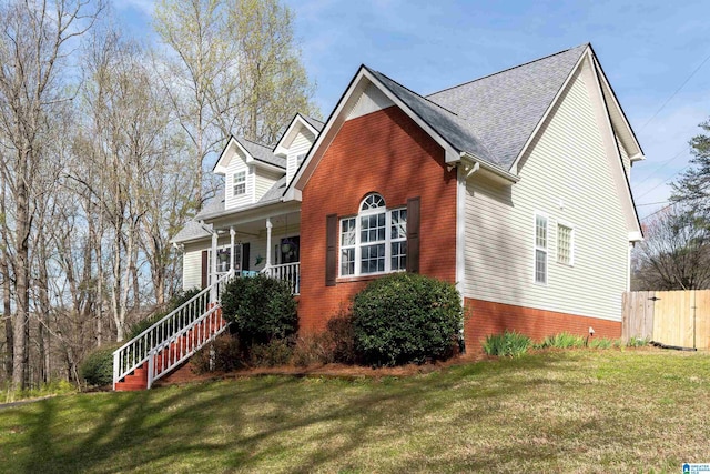 view of front of house with covered porch, a front yard, fence, and stairway