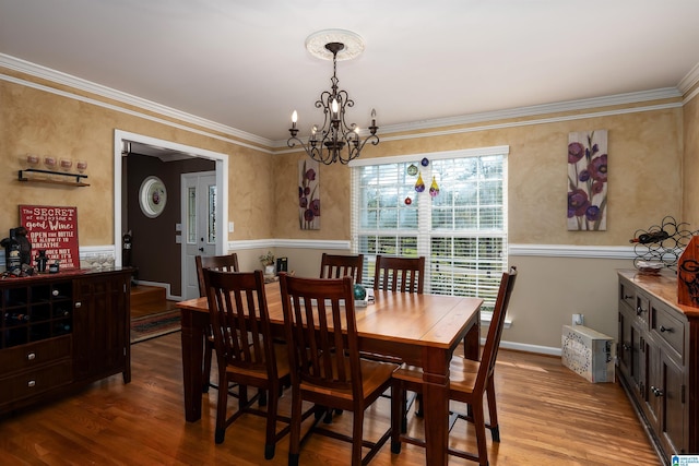 dining area with crown molding, baseboards, an inviting chandelier, and wood finished floors