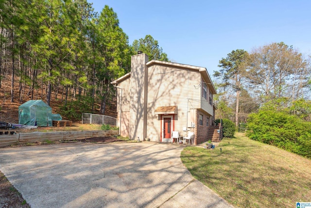 view of front of home featuring a front yard, concrete driveway, and a chimney