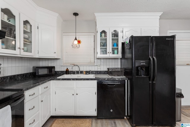 kitchen featuring white cabinetry, backsplash, a sink, black appliances, and glass insert cabinets