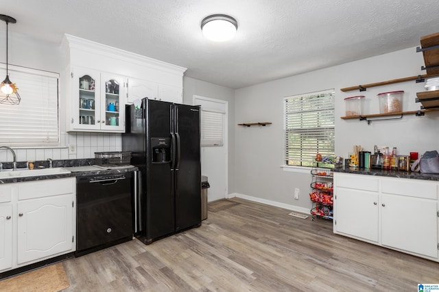 kitchen with a sink, open shelves, white cabinetry, dark countertops, and black appliances