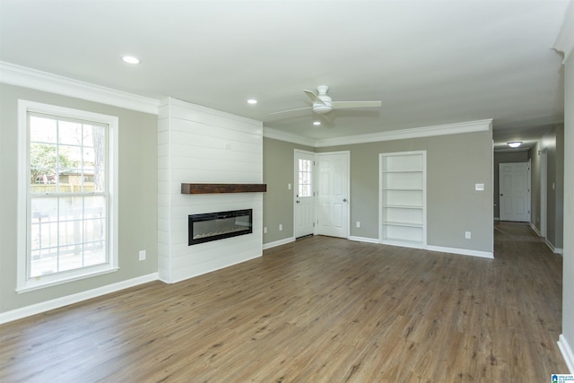 unfurnished living room with wood finished floors, built in features, ornamental molding, and a ceiling fan