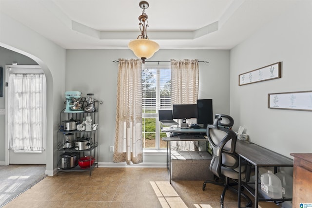tiled office featuring arched walkways, baseboards, and a raised ceiling
