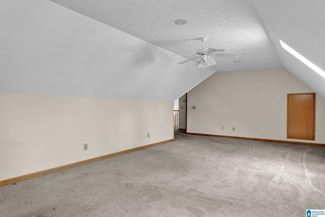 bonus room with vaulted ceiling, carpet flooring, a ceiling fan, a textured ceiling, and baseboards