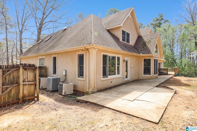 rear view of property with a patio area, roof with shingles, central air condition unit, stucco siding, and fence