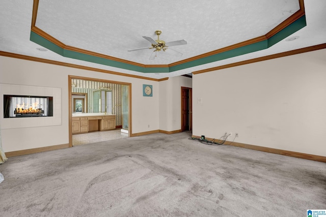 unfurnished living room featuring a textured ceiling, crown molding, carpet, a ceiling fan, and a raised ceiling