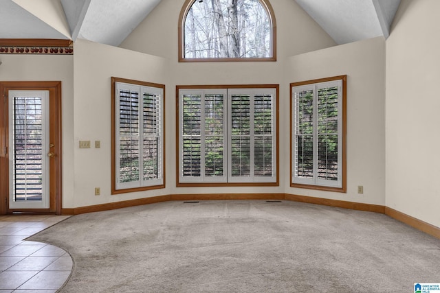 interior space featuring baseboards, carpet flooring, and high vaulted ceiling