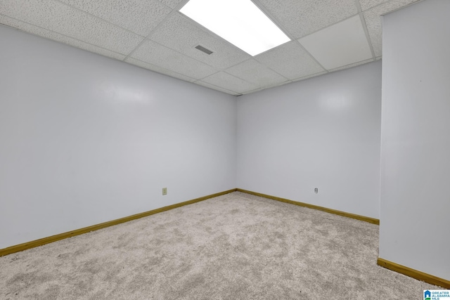 spare room with baseboards, visible vents, a drop ceiling, and carpet