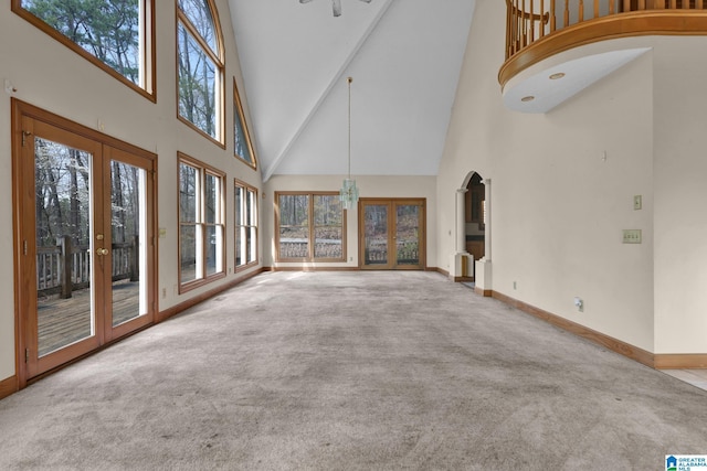 unfurnished living room featuring a towering ceiling, baseboards, carpet floors, and french doors