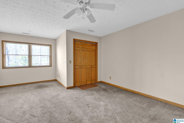 unfurnished bedroom with a textured ceiling, visible vents, baseboards, ceiling fan, and carpet floors