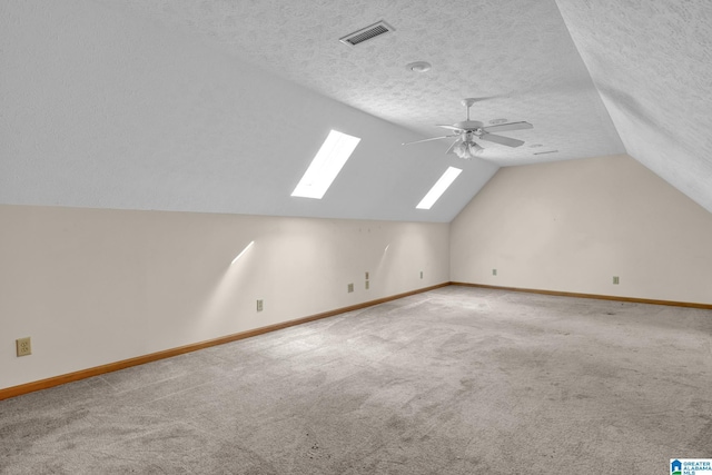additional living space with baseboards, visible vents, a ceiling fan, and a textured ceiling
