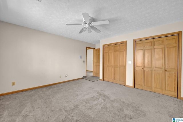 unfurnished bedroom with baseboards, multiple closets, carpet flooring, and a textured ceiling