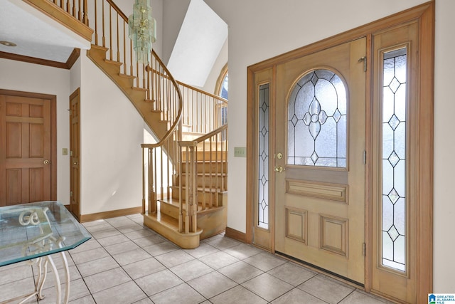 tiled foyer featuring crown molding, baseboards, and stairs