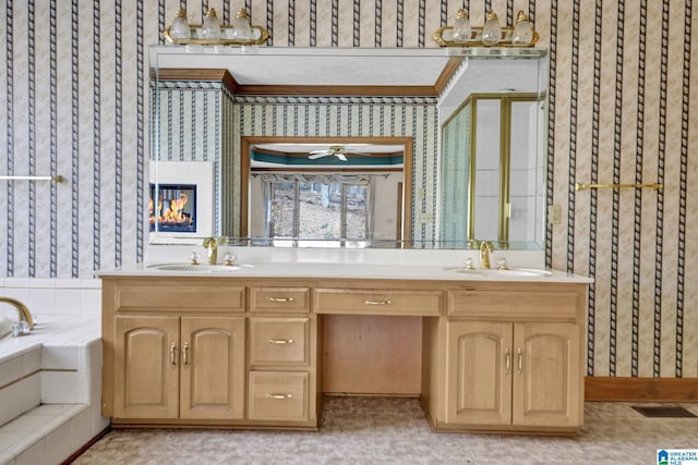 bathroom featuring a sink, double vanity, wallpapered walls, and a garden tub