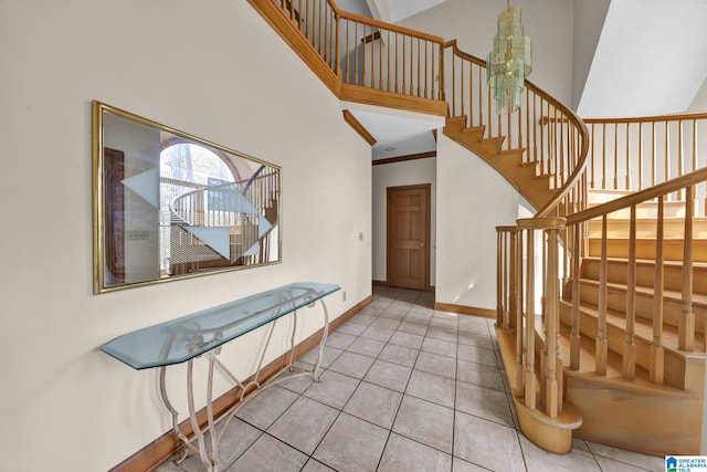 tiled foyer featuring a high ceiling, ornamental molding, baseboards, and stairs