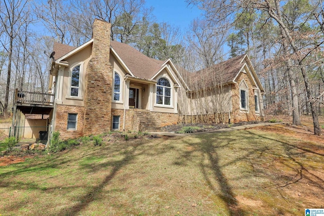 view of front of property with a wooden deck, a chimney, stucco siding, and a front lawn