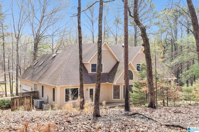 back of property with cooling unit, stucco siding, fence, roof with shingles, and a patio