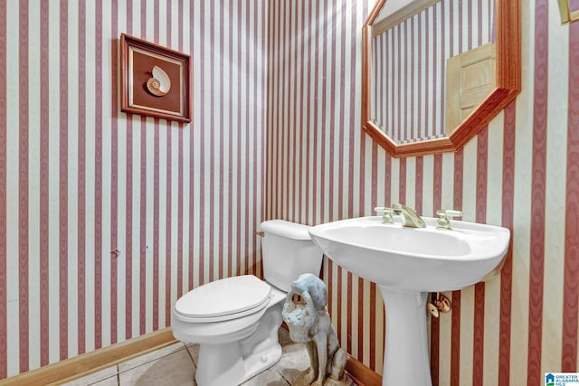 half bathroom with wallpapered walls, toilet, and tile patterned floors