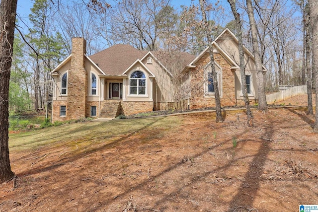 view of front of property with a front lawn, a chimney, stucco siding, and fence