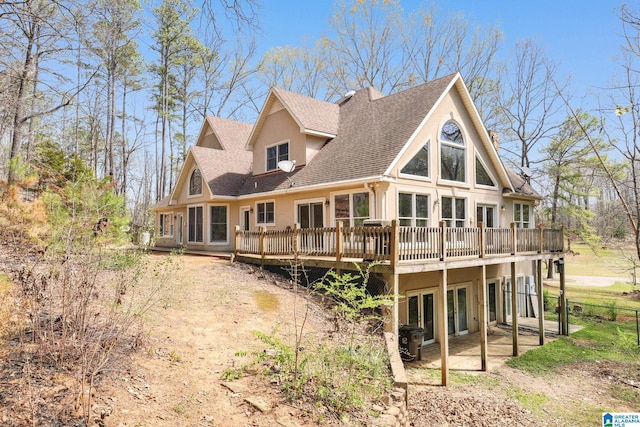 back of property with a patio area, stucco siding, a deck, and roof with shingles