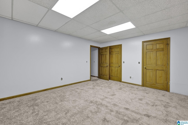 unfurnished bedroom featuring baseboards, carpet flooring, and a drop ceiling