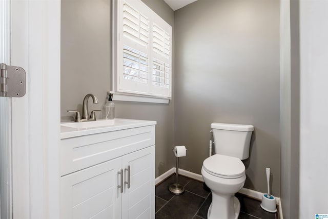 half bathroom with baseboards, toilet, tile patterned flooring, and vanity