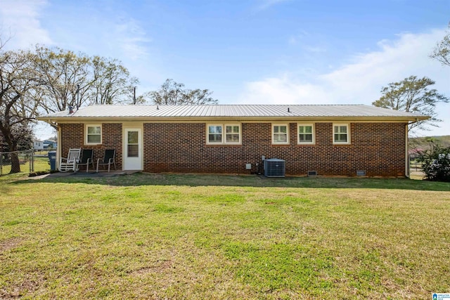 rear view of property with brick siding, fence, a yard, and metal roof