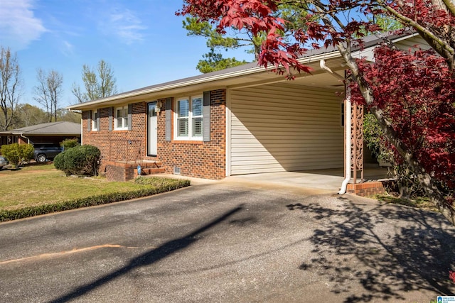 single story home with an attached carport, a front yard, brick siding, and driveway