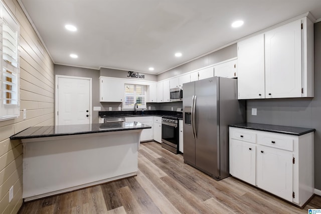 kitchen featuring white cabinets, a peninsula, stainless steel appliances, a sink, and light wood-type flooring