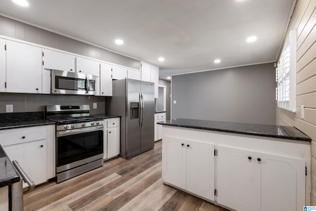 kitchen featuring white cabinets, light wood-style flooring, appliances with stainless steel finishes, and a peninsula